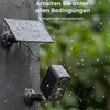 A security camera and its solar panel are mounted on a wall during a rain shower. Náhled obrázku produktu