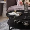A close-up of a black coffee table with books, flowers, and a cup. Produktbild-Vorschau