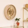A beige and gold mechanical wall clock with Roman numerals is displayed on a white wall above a glass-top table. Voir les images du produit