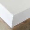 A close-up view of a white fitted sheet on a bed. Náhľad obrázku produktu