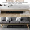 A black floor chair is shown stored under a bed and then placed in front of a sofa. Produktbild-Vorschau