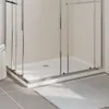 A close-up view of a white rectangular shower tray with chrome framing, set against a tiled wall and a grey tiled floor with a white bath mat. Produktbild-Vorschau