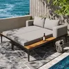 An outdoor patio daybed with cushions, a bottle of wine, a glass, and an ice bucket next to a swimming pool. Anteprima dell’immagine prodotto
