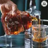 A hand is pouring amber liquid from a Stormtrooper-shaped decanter into a glass that also has a Stormtrooper design inside. Produktbild-Vorschau