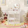 A child's white vanity desk and chair are set up in a festive, possibly Christmas-themed, room. The desk has a round mirror and drawers, and it's decorated with small toy bottles and a figurine. A plush reindeer toy and decorated Christmas trees are also v Náhled obrázku produktu