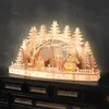 A wooden Christmas village scene with illuminated windows and trees, displayed on a dark dresser. Voir les images du produit