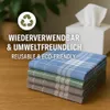 A stack of folded handkerchiefs in various colors on a wooden surface, with a tissue box and a plant in the background. Produktbild-Vorschau