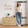 A woman stands next to a wooden dresser with shelves on the wall behind her. A height chart is on the right side of the image. Podgląd zdjęcia produktu