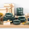 A collection of tableware, including plates and bowls, arranged on a wooden surface with gift boxes and decorative elements. Náhled obrázku produktu
