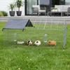 A wire cage for small animals is set up on a grassy lawn in front of a modern house with outdoor furniture. Náhľad obrázku produktu