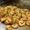 A close-up view of seasoned shrimp being cooked on a grill. Produktbild-Vorschau