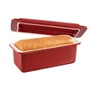 A red loaf pan with a loaf of bread inside and its lid slightly ajar, set against a white background. Podgląd zdjęcia produktu