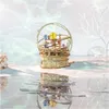 A wooden 3D puzzle of a solar system model is displayed on a surface that appears to be sand, with its reflection visible in water. Voir les images du produit