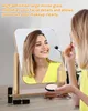 A woman is applying makeup using a tabletop mirror. Produktbild-Vorschau