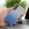 A hand holding a clear phone case with a blue gradient on a laptop. Produktbild-Vorschau