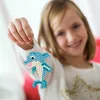 A young girl is holding up a handmade dolphin keychain made of beads. Náhled obrázku produktu