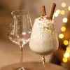 A festive drink in a wine glass, with an empty wine glass in the background and bokeh lights. Produktbild-Vorschau
