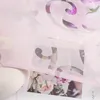 A close-up view of a pink sheer curtain with a floral burnout pattern, layered over a photograph of a bouquet of flowers. A portion of a white textured vase is visible on the left. Produktbild-Vorschau