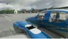 Two blue airplanes parked on an airport tarmac with mountains and buildings in the background. Náhľad obrázku produktu