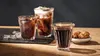 Three glasses of iced coffee and cookies on a wooden table. Produktbild-Vorschau