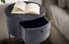 A round, dark gray nightstand with an open drawer is next to a bed. Anteprima dell’immagine prodotto