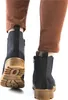 A person wearing brown pants and white socks is walking away from the camera, wearing blue Chelsea boots with brown soles. Produktbild-Vorschau