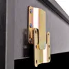 A close-up of a metal bracket attached to a dark wooden surface. Produktbild-Vorschau