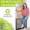 A woman is sitting on a black baby gate in a doorway, with a baby playing in the background. Produktbild-Vorschau