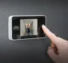 A hand is shown interacting with a digital door viewer mounted on a wall. The viewer displays a woman walking down a hallway. Produktbild-Vorschau