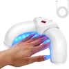 A hand with painted nails is placed inside a white UV nail lamp, which is emitting blue light. Voir les images du produit