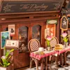 A miniature diorama of a coffee shop interior with tables, chairs, and decorative elements. Podgląd zdjęcia produktu