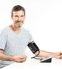 A man is using a blood pressure monitor connected to his arm and a smartphone. Náhled obrázku produktu