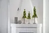 Three decorative Christmas trees with lights on a white mantelpiece. Produktbild-Vorschau