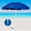 A blue beach umbrella with a white pole is set up on a sandy beach with the ocean and sky in the background. A close-up inset shows the screw-like base of the umbrella pole. Voir les images du produit