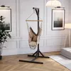 A hammock chair with a stand is set up in a well-decorated living room with artwork and a floor lamp. Podgląd zdjęcia produktu