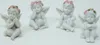 Four white cherub figurines with pink and green flower wreaths on their heads, sitting on a white background. Produktbild-Vorschau