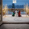 Two children building a snowman on a snowy deck with decorative lights. Podgląd zdjęcia produktu