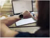 A person wearing a smartwatch is looking at it while working on a laptop. Produktbild-Vorschau