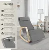 A gray rocking chair with wooden accents is shown in a living room setting, with text overlays describing its features. Náhled obrázku produktu