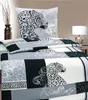 A bed with leopard-print bedding and a pillow, with a vase of branches and a lamp in the background. Produktbild-Vorschau