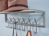 A close-up shot of a metal wall-mounted coat rack with a shelf, holding a hat and a basket. Produktbild-Vorschau