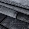 A close-up view of a folded carpet with a geometric pattern. Voir les images du produit
