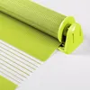A close-up view of a green roller blind, partially unrolled, showing its fabric texture and the mechanism for attachment. Produktbild-Vorschau