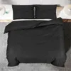 A black duvet cover and two pillowcases are laid out on a bed. Voir les images du produit