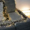 A string of warm white LED cluster lights is draped over a gray sofa, with a patterned pillow visible on the left. Produktbild-Vorschau