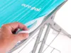 A hand is shown lifting the edge of a turquoise ironing board cover to reveal the padding underneath. Produktbild-Vorschau