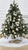A decorated Christmas tree with ornaments and a white tree skirt. Produktbild-Vorschau