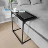 A black C-shaped side table with a laptop, a cup of coffee, and a book on it, placed next to a bed. Produktbild-Vorschau