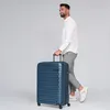 A man is walking and pulling a blue suitcase. Produktbild-Vorschau