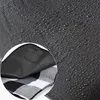 Close-up view of a waterproof picnic blanket showing water droplets on the dark grey outer layer and a glimpse of the black and white checkered pattern underneath. Anteprima dell’immagine prodotto